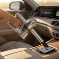 Handheld portable vacuum cleaner being used to clean a modern car interior with sunlight streaming through the window